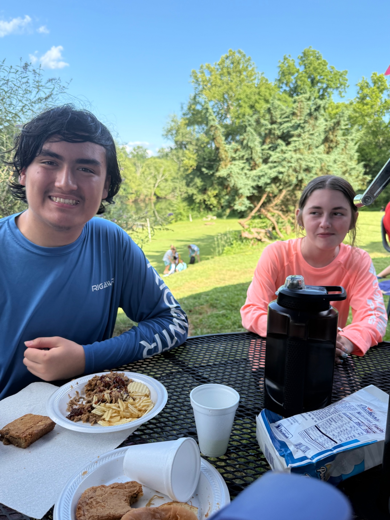 Two students sharing a cookout lunch by the water at camp