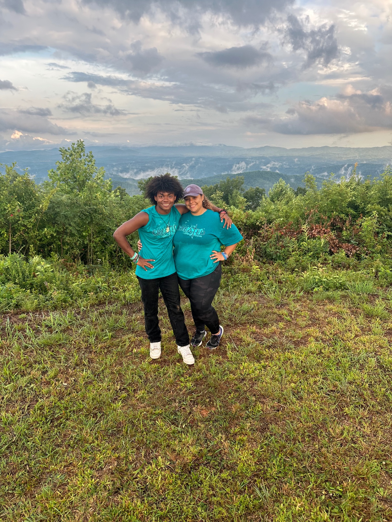 Two students in camp shirts at a mountain overlook