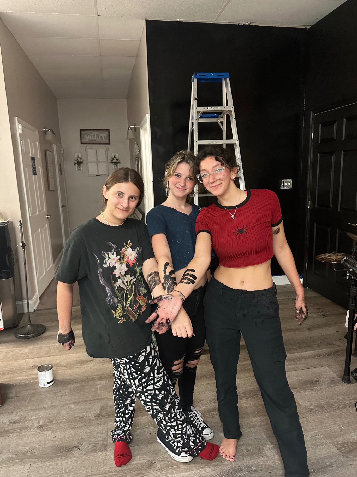 Three teens covered in paint after setting up the gathering space