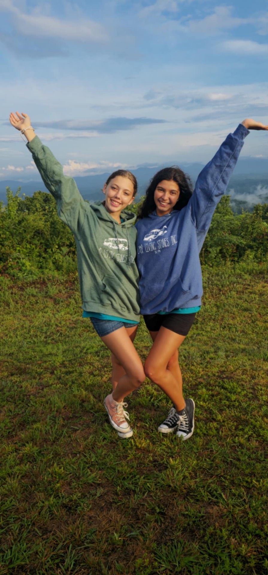 Two friends with arms raised at sunset on the mountain