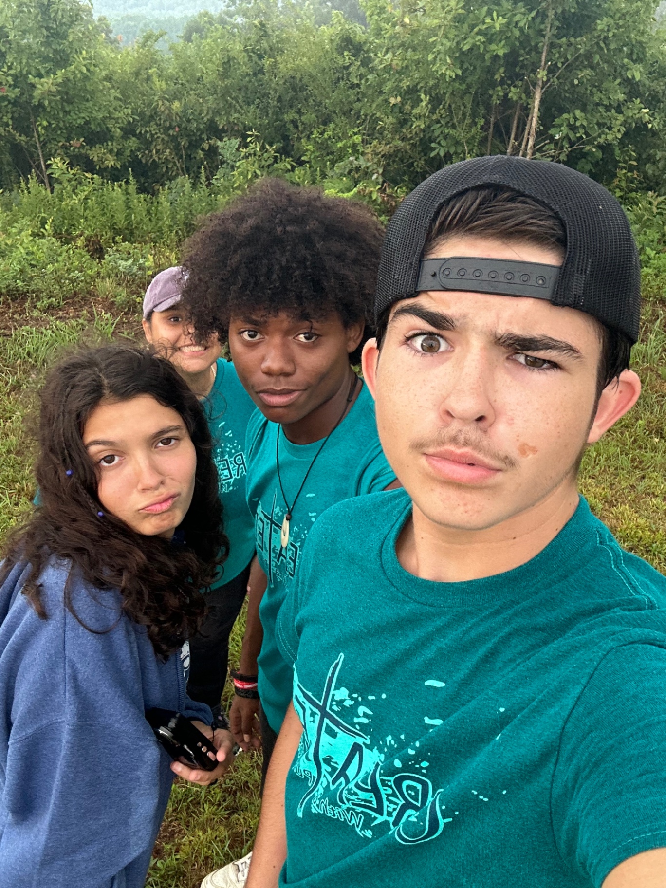 A group of teens taking a selfie in a mountain field