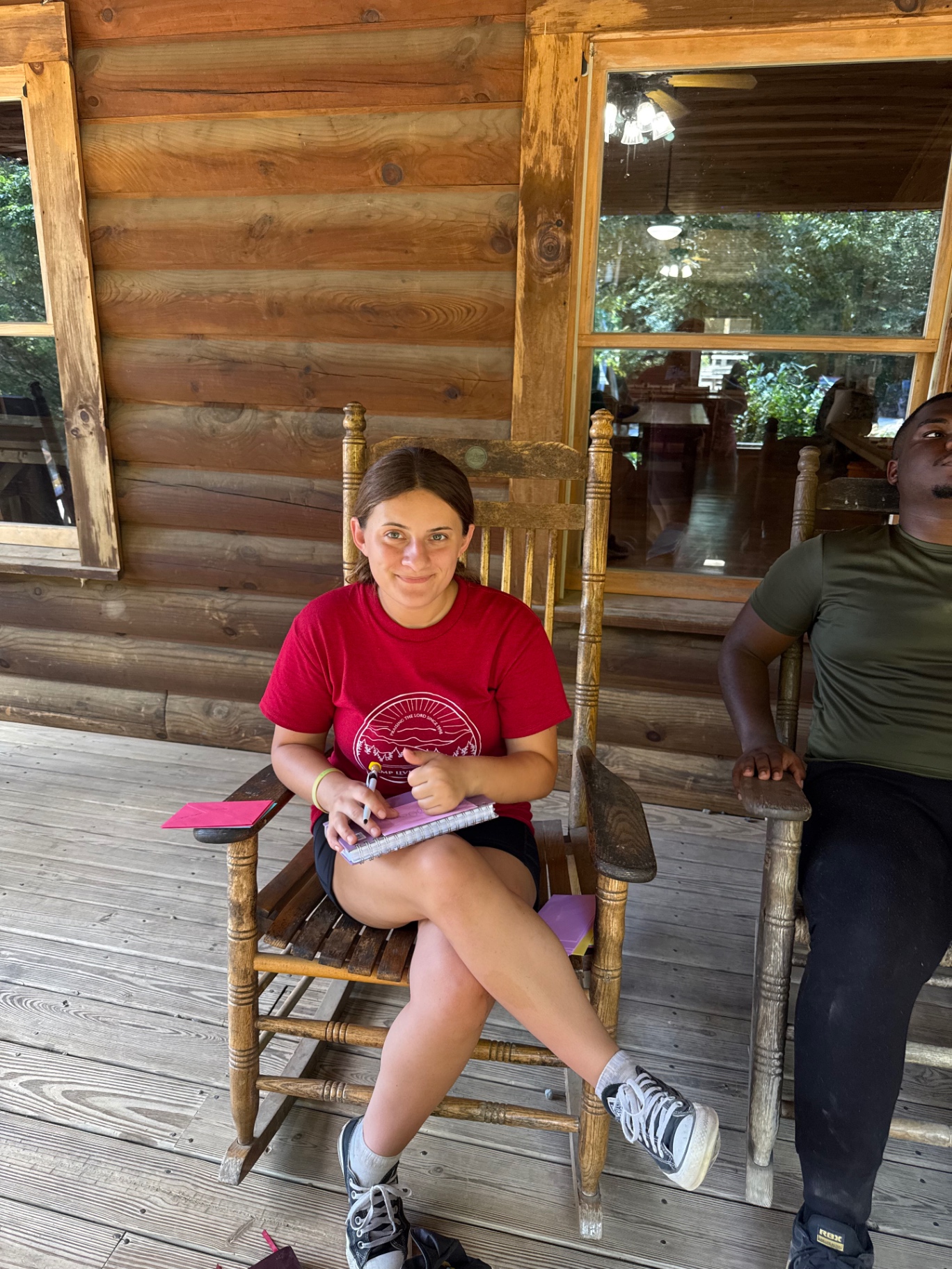 A student journaling in a rocking chair on the cabin porch